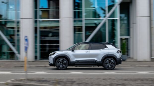 Toyota Urban Cruiser in Silber, Seitenansicht während der Fahrt, vor Glasfassaden in der Stadt.