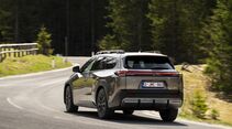 Toyota bZ4X Touring AWD in Heckansicht auf kurviger Straße im Waldgebiet