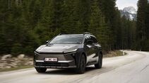 Toyota bZ4X Touring AWD während der Fahrt auf einer Landstraße im Waldgebiet