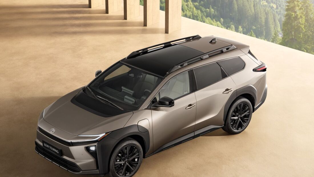 Toyota bZ4X Touring als Elektro-SUV in schräger Draufsicht, mit schwarzem Dach, Dachreling und schwarzer Leichtmetallfelge in moderner Architektur