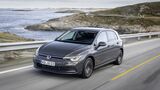 VW Golf E-Hybrid in Grau fährt auf einer Küstenstraße entlang einer felsigen Meereslandschaft.