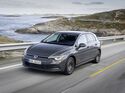 VW Golf E-Hybrid in Grau fährt auf einer Küstenstraße entlang einer felsigen Meereslandschaft.