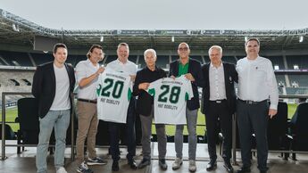 Vertreter von akf-Mobility und Borussia Mönchengladbach präsentieren im Stadion zwei Trikots zur neuen Mobilitätspartnerschaft.