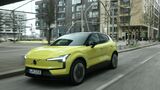Volvo EX30 P8 AWD Electric in Gelb bei einer Fahraufnahme im Stadtverkehr, schräg von vorne fotografiert.