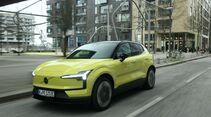 Volvo EX30 P8 AWD Electric in Gelb bei einer Fahraufnahme im Stadtverkehr, schräg von vorne fotografiert.