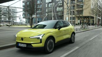 Volvo EX30 P8 AWD Electric in Gelb bei einer Fahraufnahme im Stadtverkehr, schräg von vorne fotografiert.