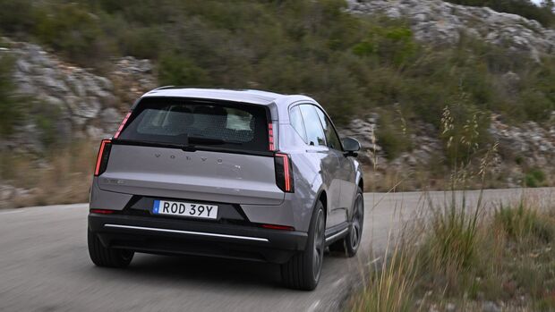 Volvo EX60 Elektro-SUV in Heckansicht auf kurviger Landstraße in bergiger Landschaft.