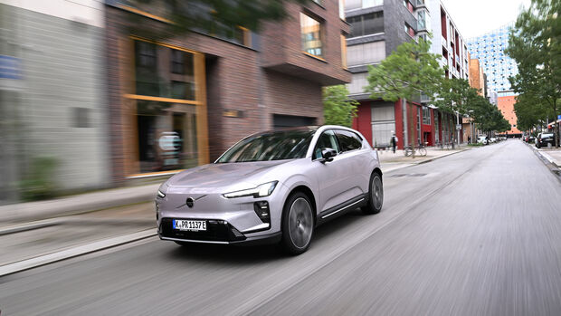 Volvo EX60 fährt durch eine innerstädtische Straße mit moderner Bebauung.