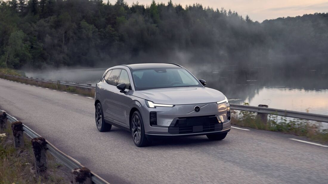 Volvo XC70 SUV in Frontansicht auf einer Landstrasse neben einem See mit Wald im Hintergrund bei Daemmerung.