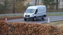 Weißer Ford E-Transit fährt auf einer Teststrecke beim Ford Pro Leisure Experience Event in Lommel, mit Pylonen und Leitplanken.