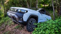 Weißer Jeep Compass 4xe fährt abseits eines befestigten Weges durch bewaldetes Gelände.