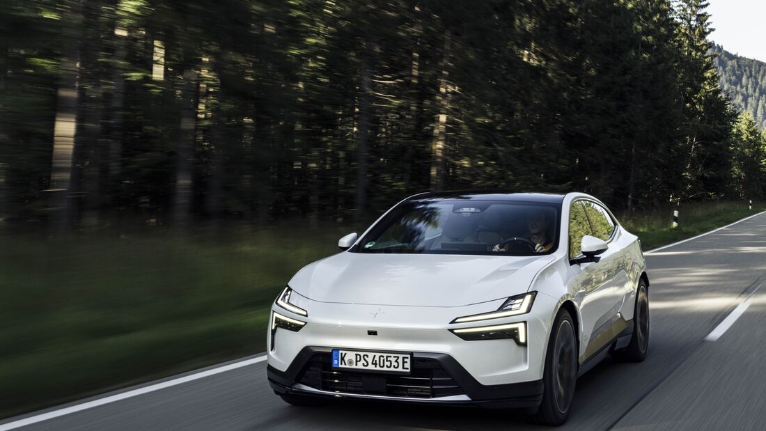 Weisser Polestar 4 faehrt auf Landstrasse durch bewaldete Landschaft