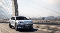 Weißer Renault Filante SUV fährt auf Brücke vor Skyline bei Sonnenaufgang