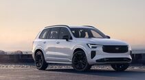 Weißer Volvo XC90 Black Edition mit schwarzem Kühlergrill und schwarzen Felgen, schräg von vorne an einer Küstenstraße fotografiert.