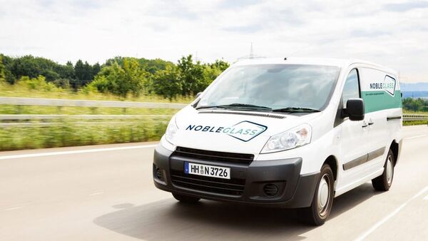 Weißer nobleglass-Transporter fährt auf der Straße, Front und Seitenlogo sichtbar, Einsatzfahrzeug im AFC-Risikomanagement.