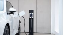 Weißes Elektroauto von Polestar lädt an einer Wandladestation in einem Innenraum.