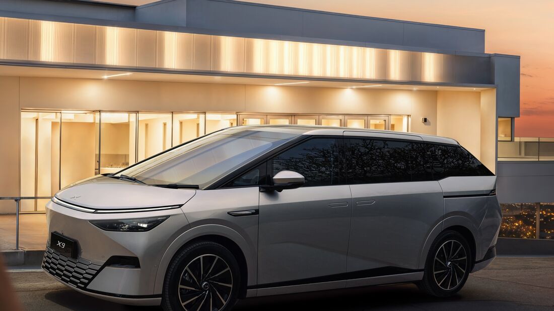 Xpeng X9 als Elektro-Van vor einem modernen Gebäude, Seitenansicht bei Dämmerung.