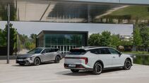 Zwei Kia K4 Sportswagon Modelle vor moderner Gebäudearchitektur.