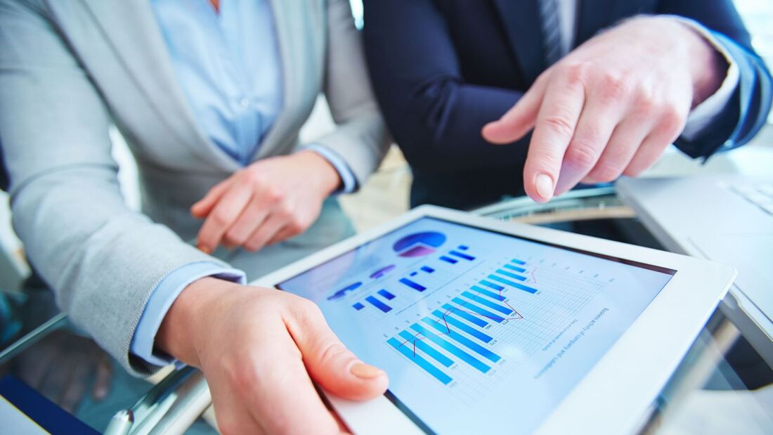 Zwei Personen analysieren auf einem Tablet Diagramme und Fahrzeugdaten zur Bewertung von Restwerten im Leasing- und Flottenmanagement.