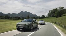 Zwei Polestar 3 Performance fahren auf einer Landstraße durch eine hügelige Landschaft.