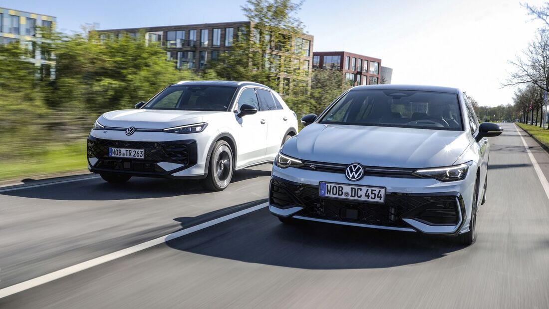 Zwei Volkswagen Modelle Golf und T-Roc Hybrid fahren nebeneinander auf einer Straße in urbaner Umgebung