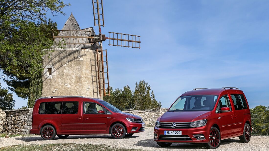 Zwei rote VW Caddy Modelle stehen nebeneinander vor einer Windmühle, Front- und Seitenansicht sichtbar