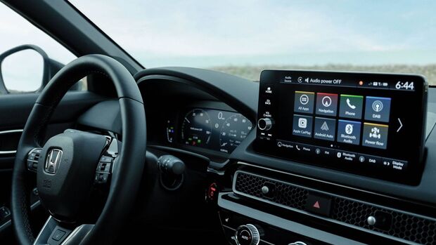 nnenraum des Honda Civic e:HEV mit Lenkrad, digitalem Kombiinstrument und zentralem Infotainment-Display.