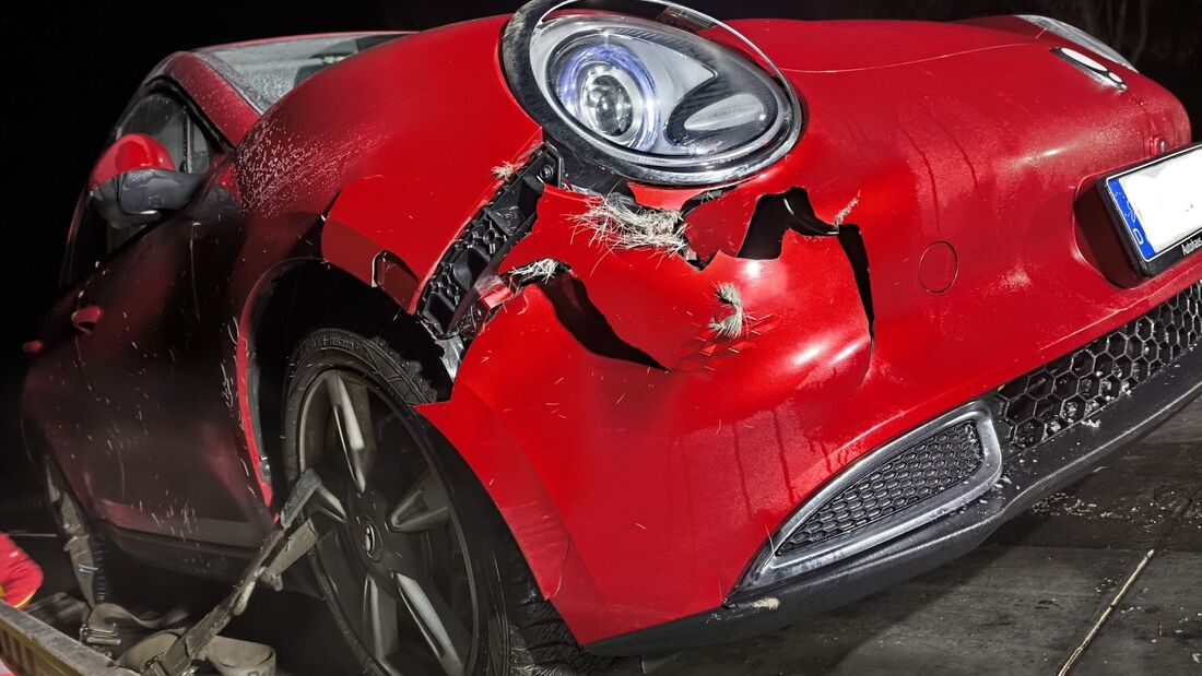 unfallauto mit starkem frontschaden auf einem abschleppwagen bei nacht